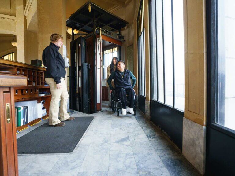 A man using a wheelchair and his companion exit an accessible elevator at Vista House.