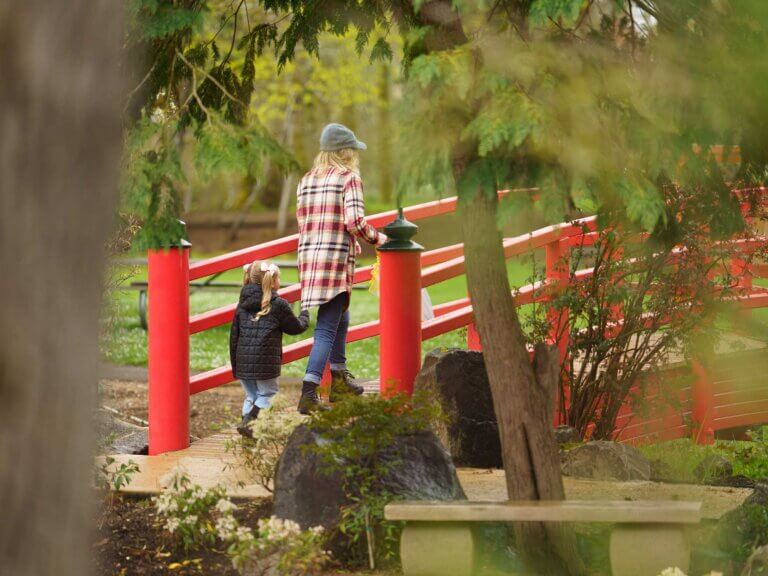 A woman and a young girl walk across a footbridge