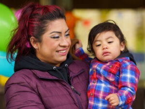 Portrait of a mother holding a small child, both dressed for outdoor weather.